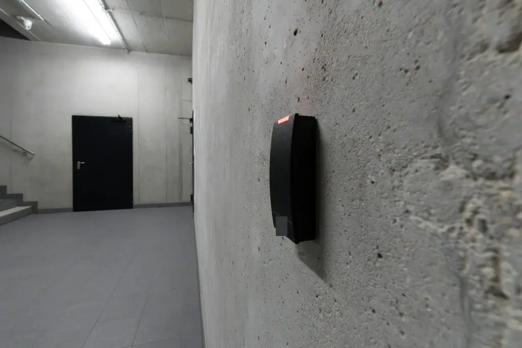 Badge card reader beside a secured door in a modern office corridor