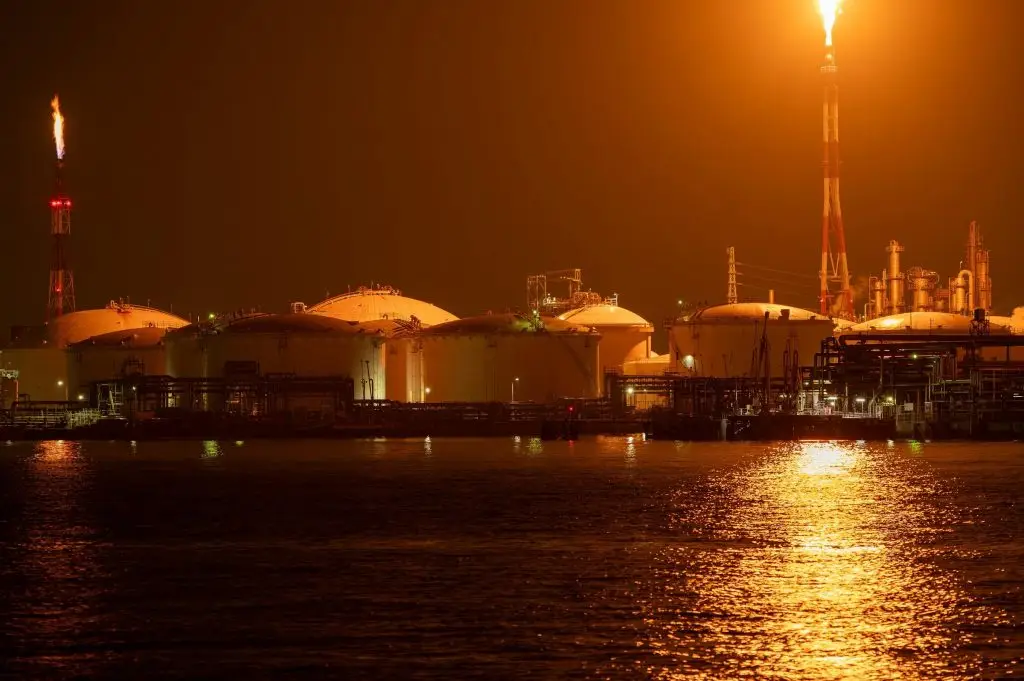Industrial tank farm and refinery lit up at night along the waterfront