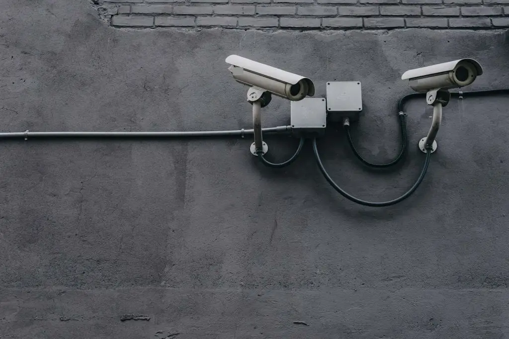 Two outdoor security cameras mounted on a commercial building wall