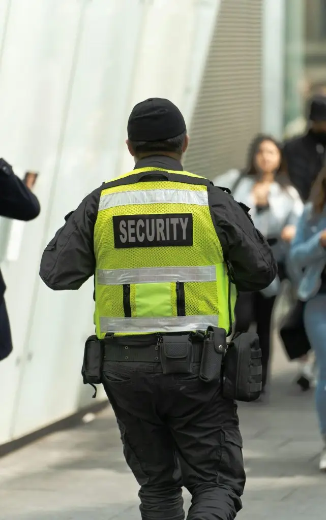 Uniformed security officer in a reflective vest on foot patrol